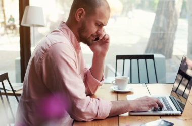 Man working from a coffee shop in a mixed-use new urban precinct